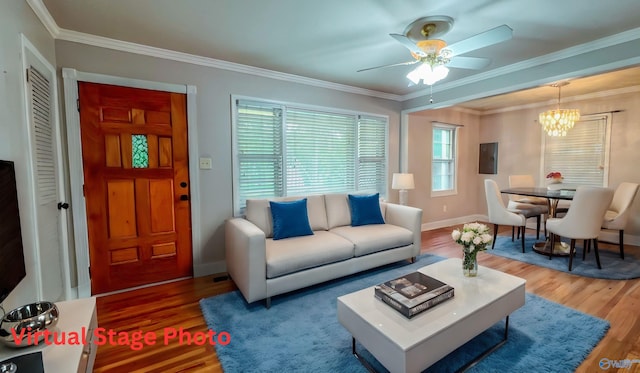 living room featuring hardwood / wood-style flooring, ceiling fan with notable chandelier, and ornamental molding