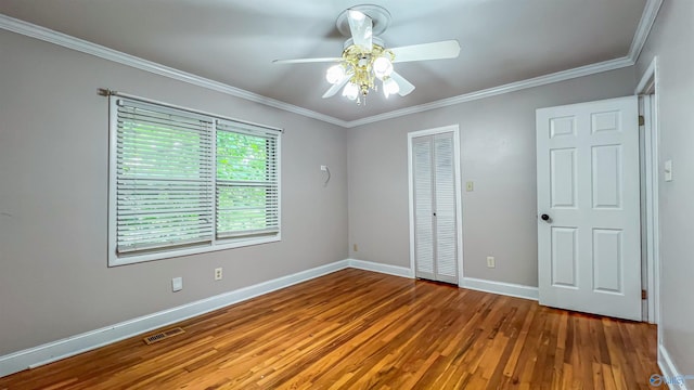 unfurnished bedroom featuring hardwood / wood-style flooring, ornamental molding, ceiling fan, and a closet