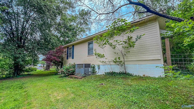 view of side of home with central AC unit and a yard