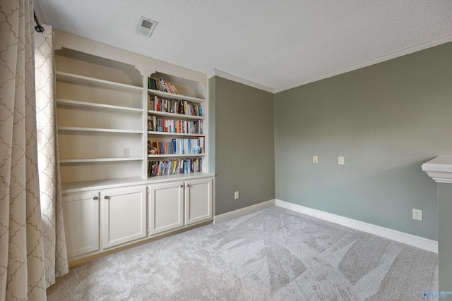 empty room with visible vents, light colored carpet, a textured ceiling, and baseboards