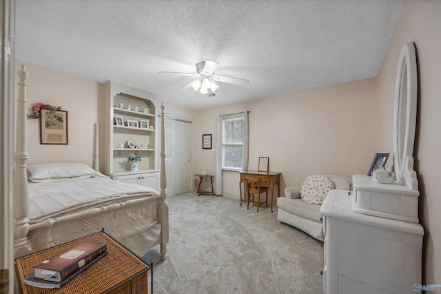 bedroom featuring a textured ceiling, ceiling fan, light colored carpet, baseboards, and a closet