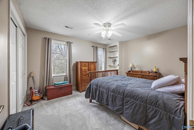 bedroom with carpet, a closet, visible vents, a ceiling fan, and a textured ceiling