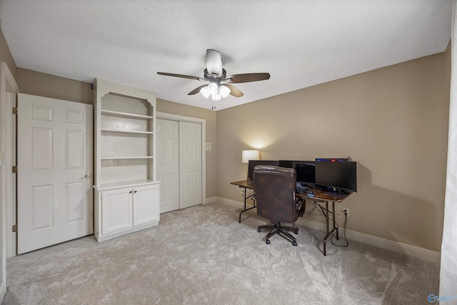 office area with light carpet, ceiling fan, a textured ceiling, and baseboards