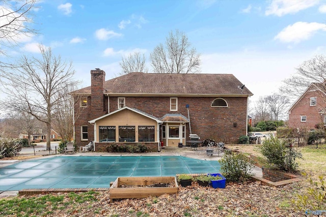 back of property with brick siding, a patio, a chimney, and fence