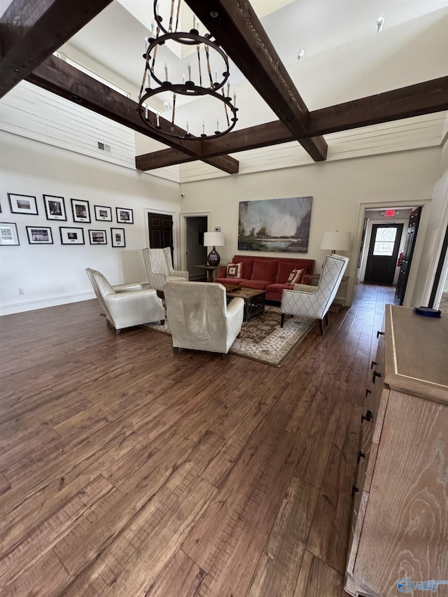 living area with beam ceiling, dark wood finished floors, visible vents, a chandelier, and baseboards