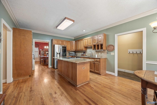 kitchen featuring light stone counters, a center island, light wood-style flooring, decorative backsplash, and a sink