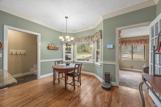 dining room featuring crown molding, a textured ceiling, wood finished floors, a chandelier, and baseboards