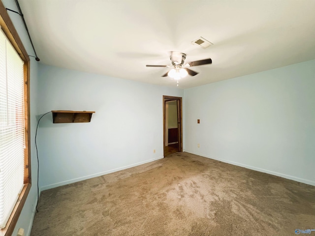carpeted empty room with ceiling fan and baseboards
