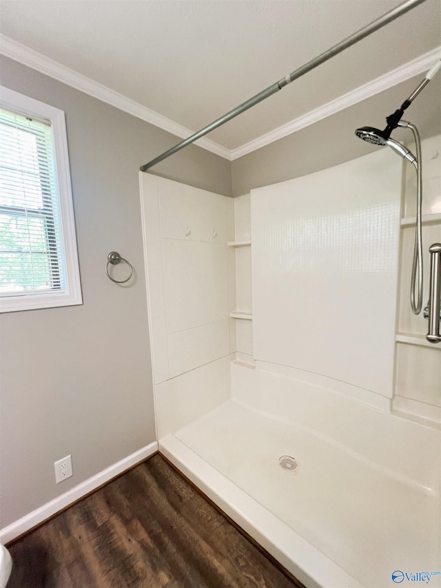 bathroom featuring wood finished floors, a shower, ornamental molding, and baseboards