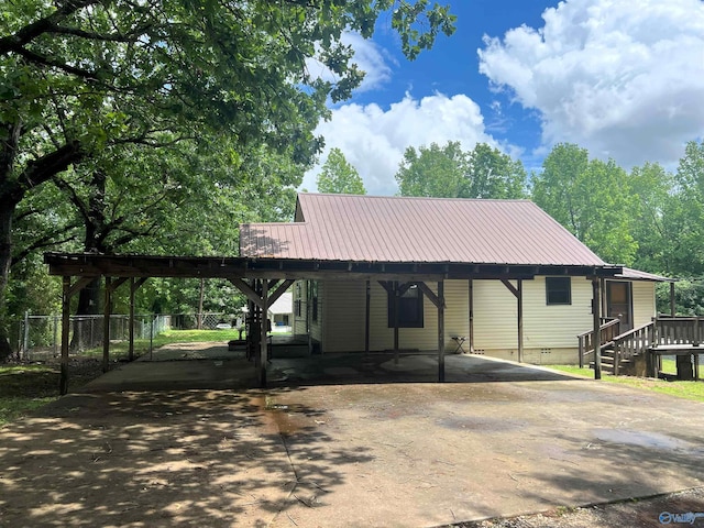 view of front of home with crawl space, a carport, asphalt driveway, metal roof, and fence