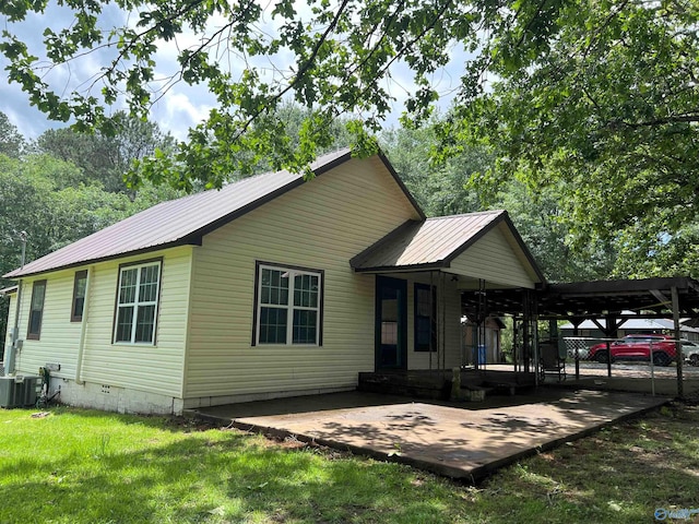view of front of property featuring metal roof, a front yard, and central air condition unit