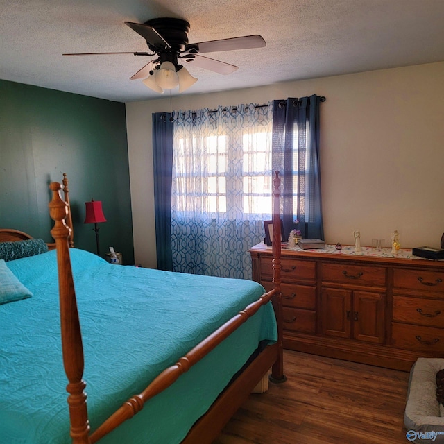 bedroom with ceiling fan, dark wood-type flooring, and a textured ceiling