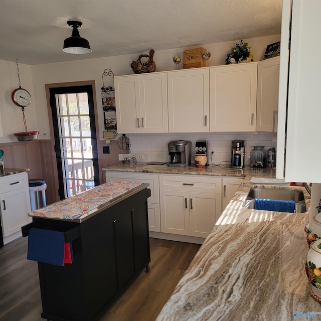 kitchen with dark hardwood / wood-style floors, sink, white cabinets, decorative backsplash, and light stone countertops