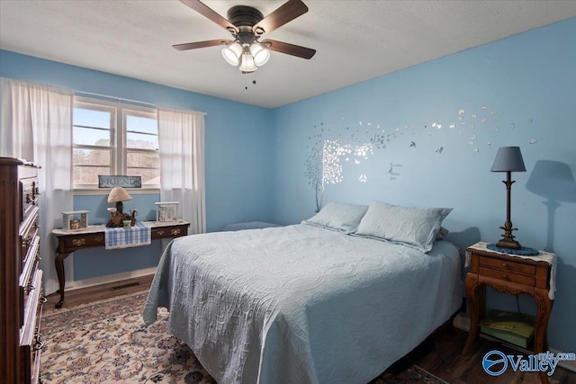 bedroom with dark wood-type flooring, ceiling fan, and a textured ceiling