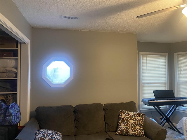 living room featuring a textured ceiling and ceiling fan