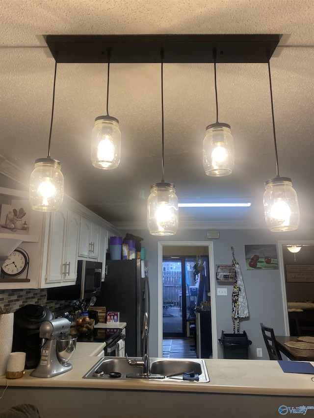 kitchen with pendant lighting, stainless steel fridge, and white cabinets