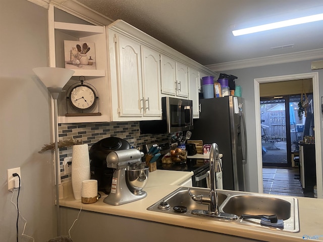 kitchen with backsplash, crown molding, white cabinets, and appliances with stainless steel finishes