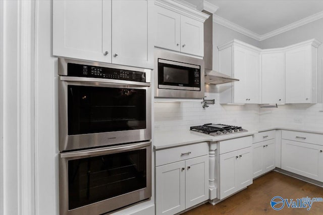 kitchen featuring appliances with stainless steel finishes, backsplash, ornamental molding, white cabinets, and dark hardwood / wood-style floors