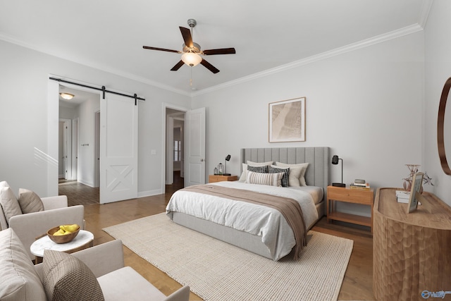 bedroom featuring hardwood / wood-style floors, a barn door, ceiling fan, and ornamental molding