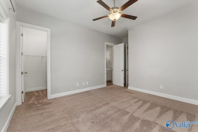 unfurnished bedroom with a closet, light colored carpet, a spacious closet, and ceiling fan