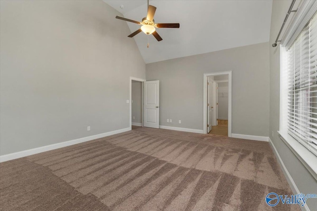 unfurnished bedroom featuring carpet, a spacious closet, high vaulted ceiling, and ceiling fan