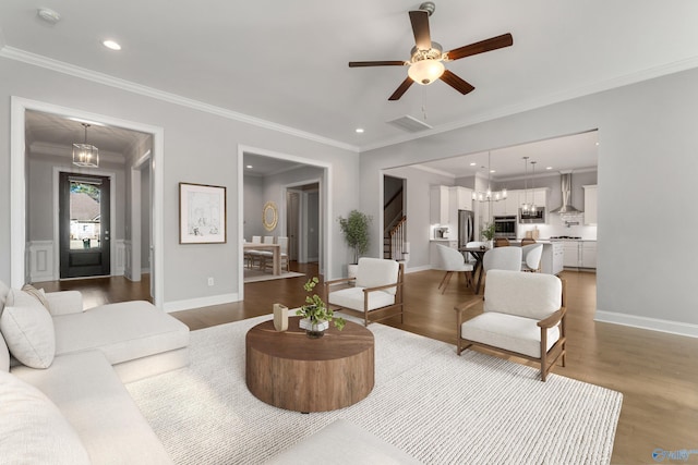 living room featuring hardwood / wood-style floors, ceiling fan with notable chandelier, and ornamental molding