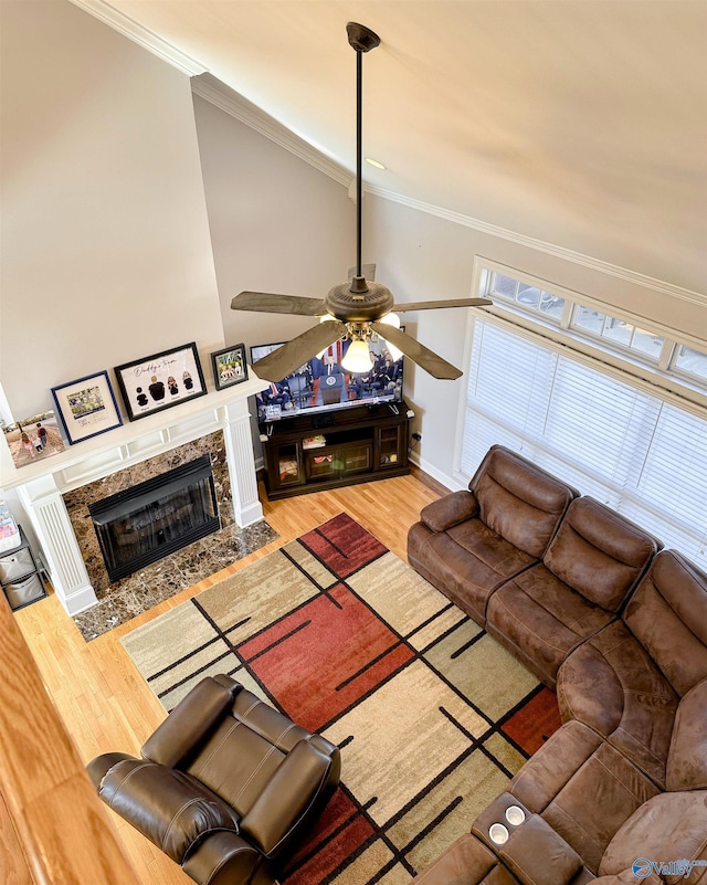 living room with ceiling fan, a high end fireplace, ornamental molding, and wood-type flooring