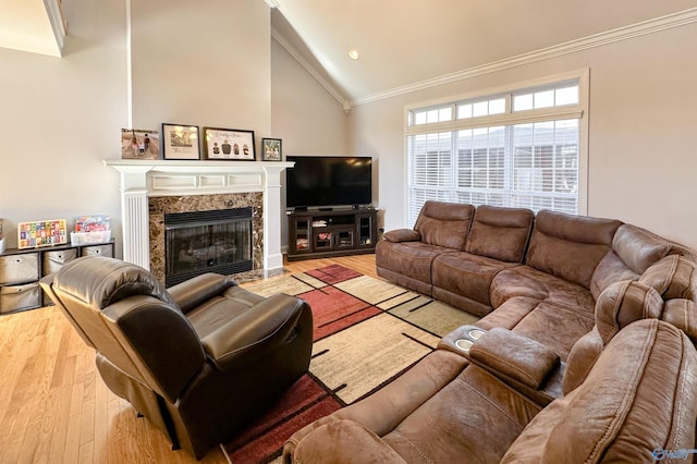 living room with light hardwood / wood-style floors, high vaulted ceiling, a high end fireplace, and ornamental molding