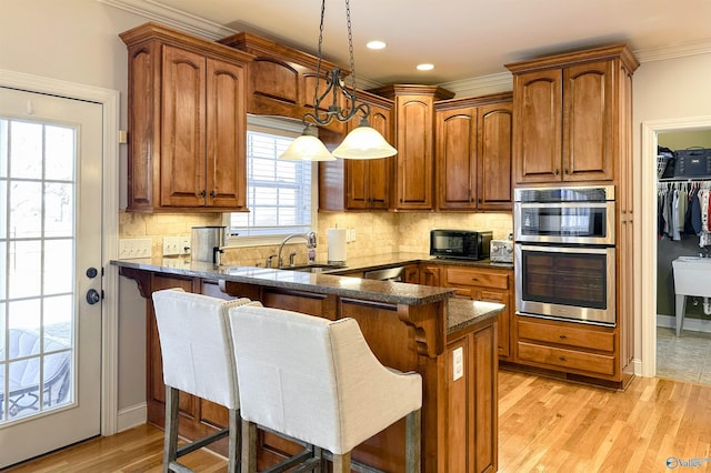 kitchen featuring decorative light fixtures, a breakfast bar area, kitchen peninsula, and dark stone countertops