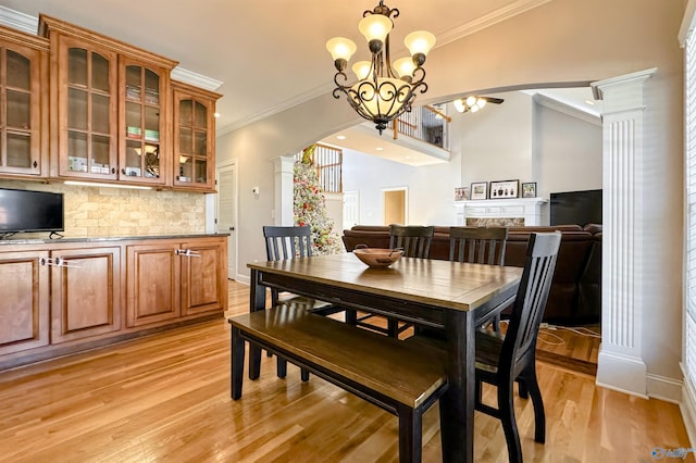 dining room featuring crown molding, light hardwood / wood-style flooring, ornate columns, and an inviting chandelier