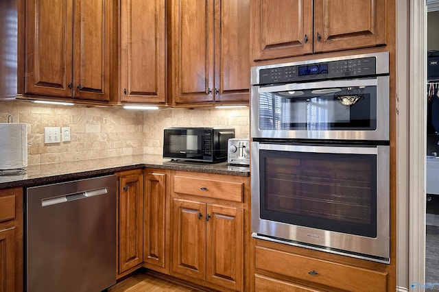 kitchen featuring tasteful backsplash, stainless steel appliances, and dark stone countertops