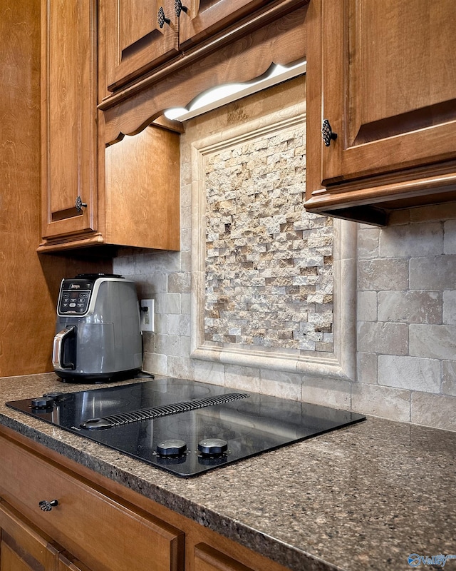 kitchen with black electric cooktop, dark stone counters, and tasteful backsplash