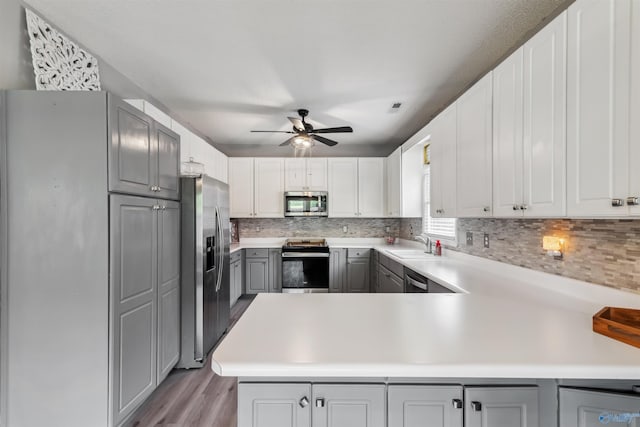 15037 SE Ashmont Blvd, Huntsville, AL 35803 - kitchen featuring stainless steel appliances, gray cabinetry, ceiling fan, backsplash, and light wood-type flooring