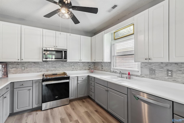 15037 SE Ashmont Blvd, Huntsville, AL 35803 - kitchen featuring appliances with stainless steel finishes, gray cabinetry, a ceiling fan, decorative backsplash, and light wood-type flooring