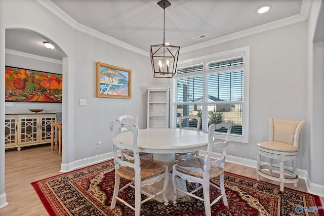 dining space featuring visible vents, ornamental molding, light wood-style flooring, arched walkways, and baseboards