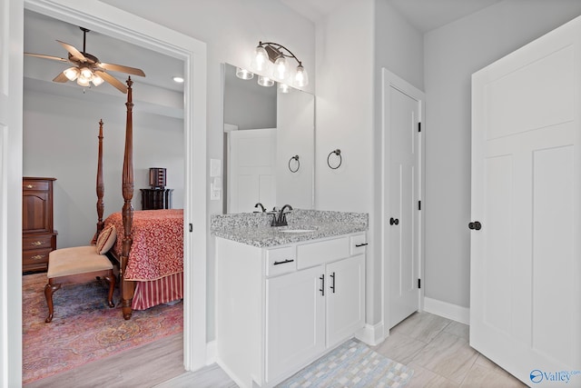 ensuite bathroom featuring baseboards, vanity, ceiling fan, and ensuite bathroom