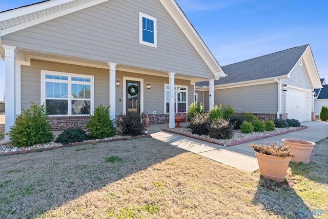 view of front facade with a garage, brick siding, covered porch, and a front lawn