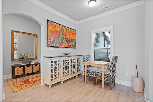 dining space featuring visible vents, crown molding, baseboards, wood finished floors, and arched walkways