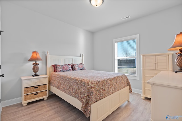 bedroom featuring baseboards, visible vents, and light wood finished floors