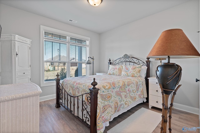 bedroom with visible vents, wood finished floors, and baseboards