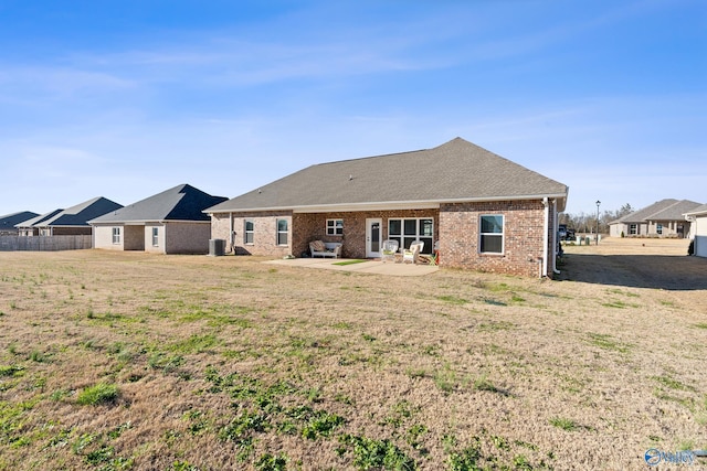 back of property featuring a yard, a patio area, brick siding, and central AC