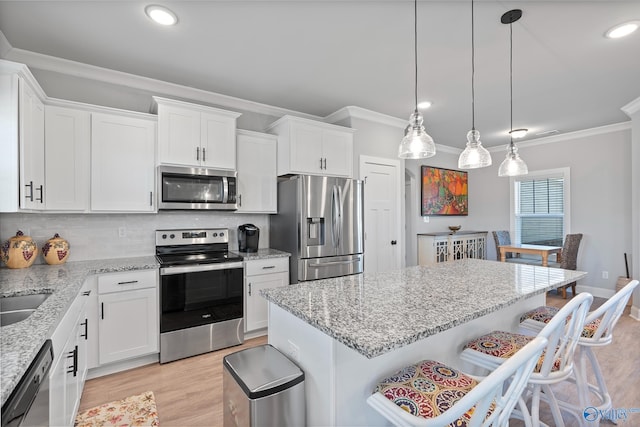 kitchen featuring white cabinetry, appliances with stainless steel finishes, a breakfast bar area, and ornamental molding