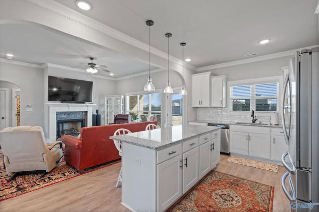 kitchen with tasteful backsplash, a high end fireplace, stainless steel appliances, light wood-style floors, and white cabinets