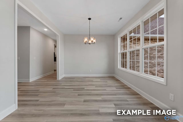 unfurnished dining area featuring baseboards, an inviting chandelier, and a wealth of natural light