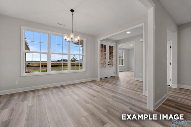 unfurnished dining area featuring baseboards, wood finished floors, a notable chandelier, and visible vents