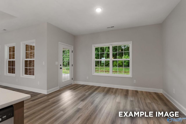 unfurnished dining area featuring visible vents, baseboards, and wood finished floors