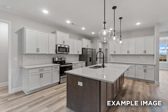 kitchen with white cabinetry, appliances with stainless steel finishes, a sink, and backsplash