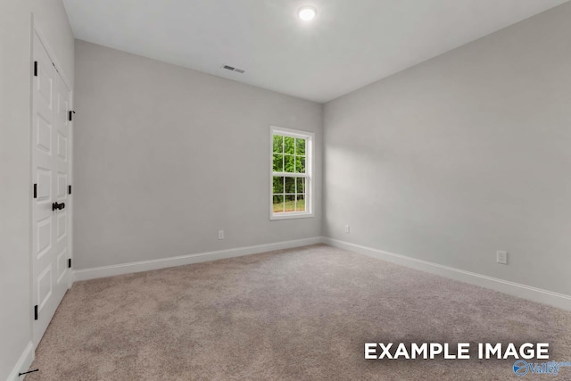 spare room with carpet flooring, baseboards, and visible vents