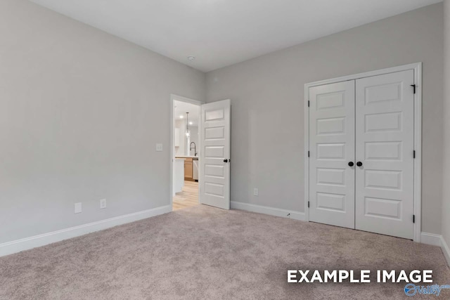 unfurnished bedroom with a closet, carpet flooring, and baseboards