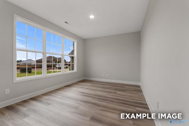 unfurnished room featuring recessed lighting, visible vents, baseboards, and wood finished floors